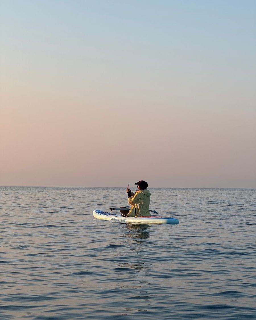 凪いだ入江の水面に、SUP ボードに立つ人が小さく見える